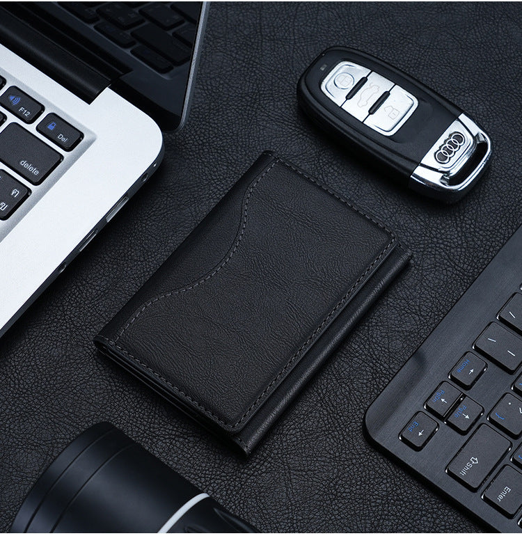 Black leather wallet and car key on a desk with a laptop and keyboard in the background