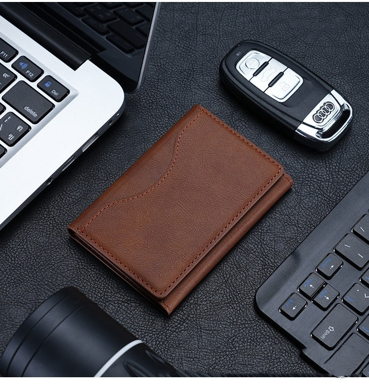 Brown leather wallet, car key, and flashlight on a dark surface with a laptop and keyboard.