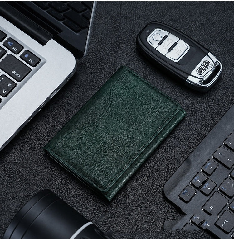 Green leather wallet, car keys, and laptop on a dark surface