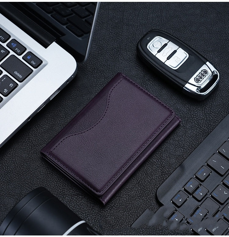 Purple leather wallet and car key fob on a desk with computer equipment.