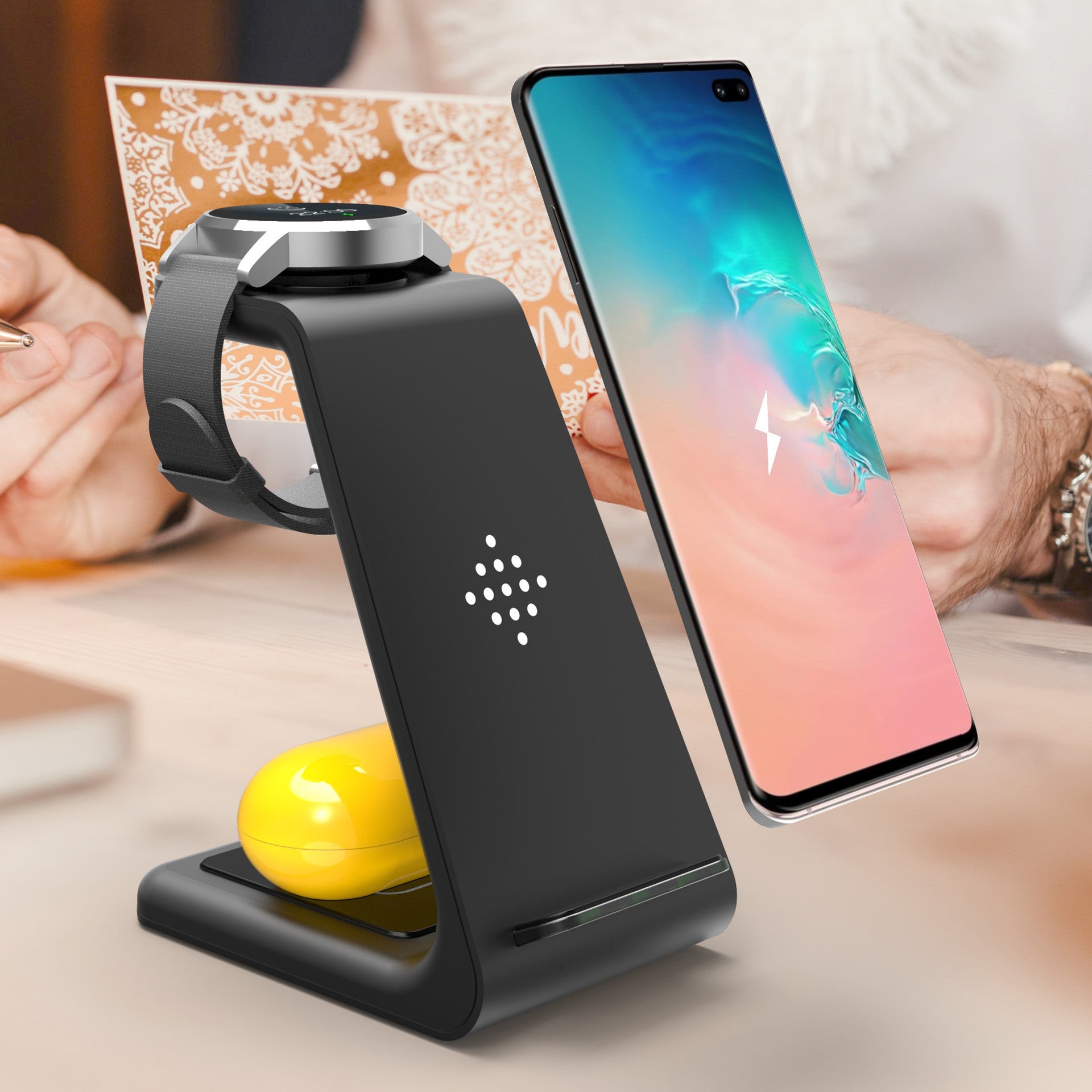 Black wireless charging stand with smartphone and smartwatch on a blurred background