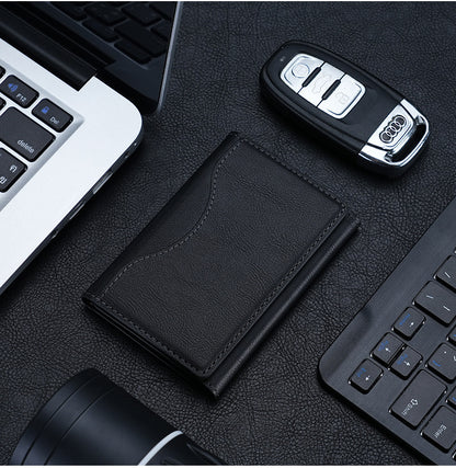 Black leather wallet and car key on a desk with a laptop and keyboard in the background