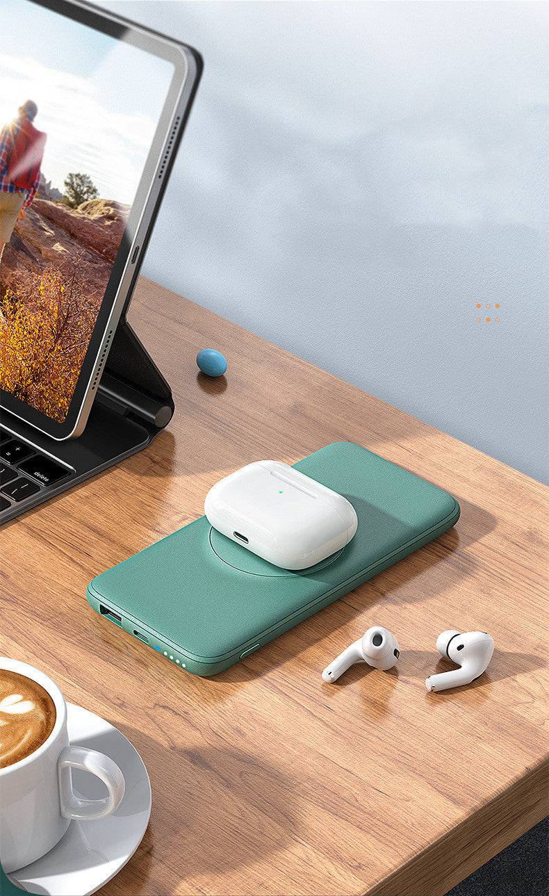 Green case with wireless earbuds on a wooden desk next to a tablet and coffee cup.