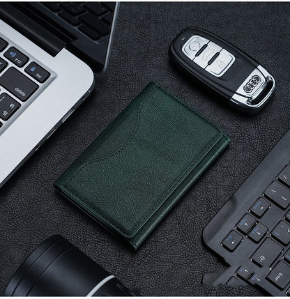Green leather wallet, car keys, and laptop on a dark surface