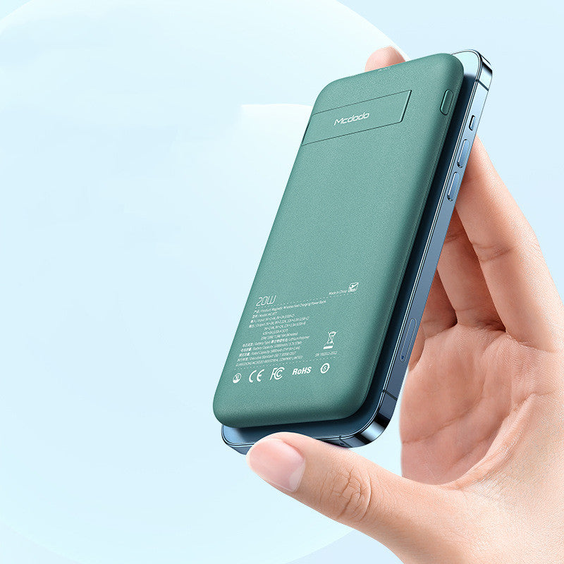 Green power bank held in a hand against a light blue background